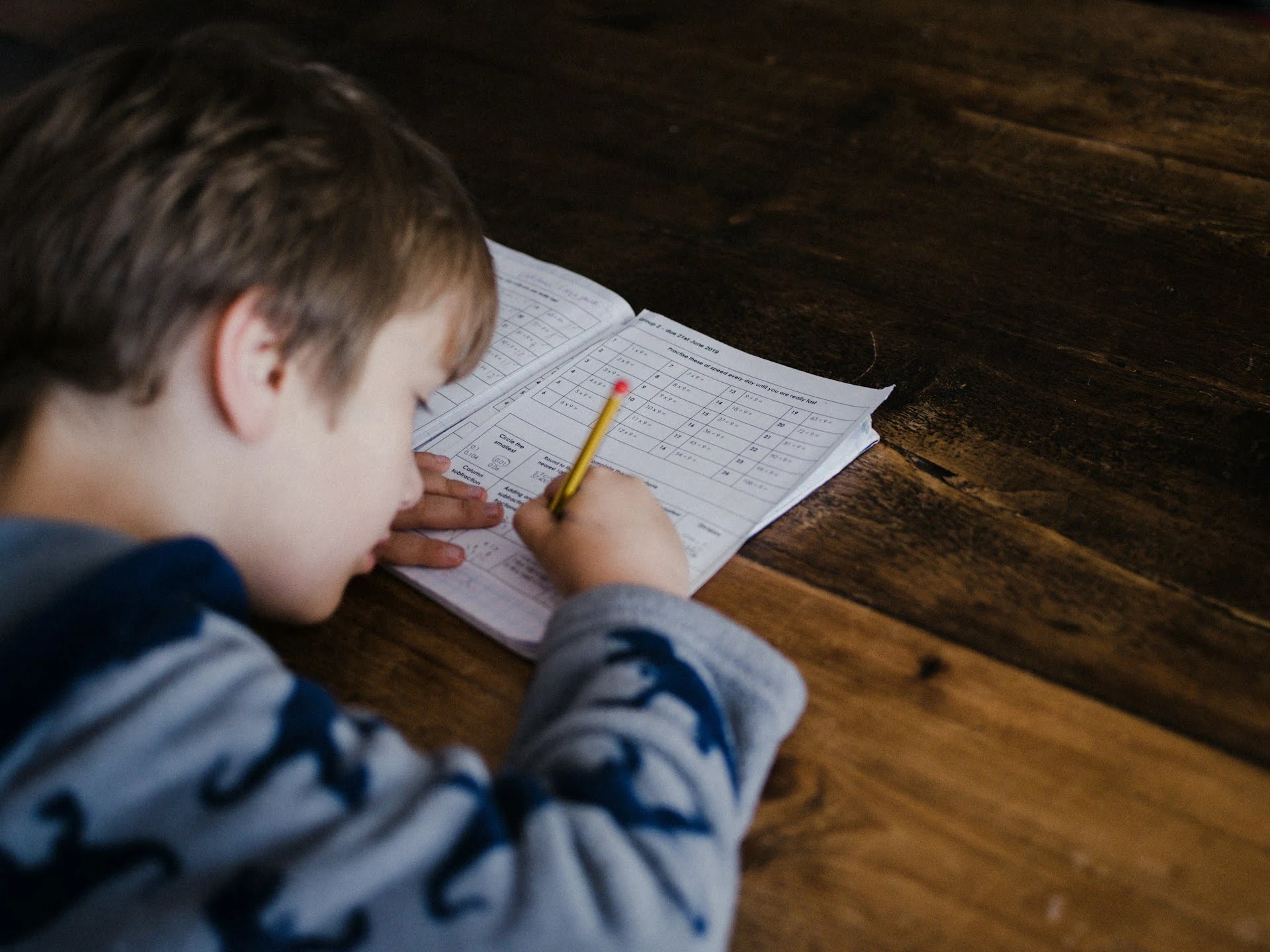 A young boy focused on writing on a piece of paper, showcasing concentration and creativity in his task.